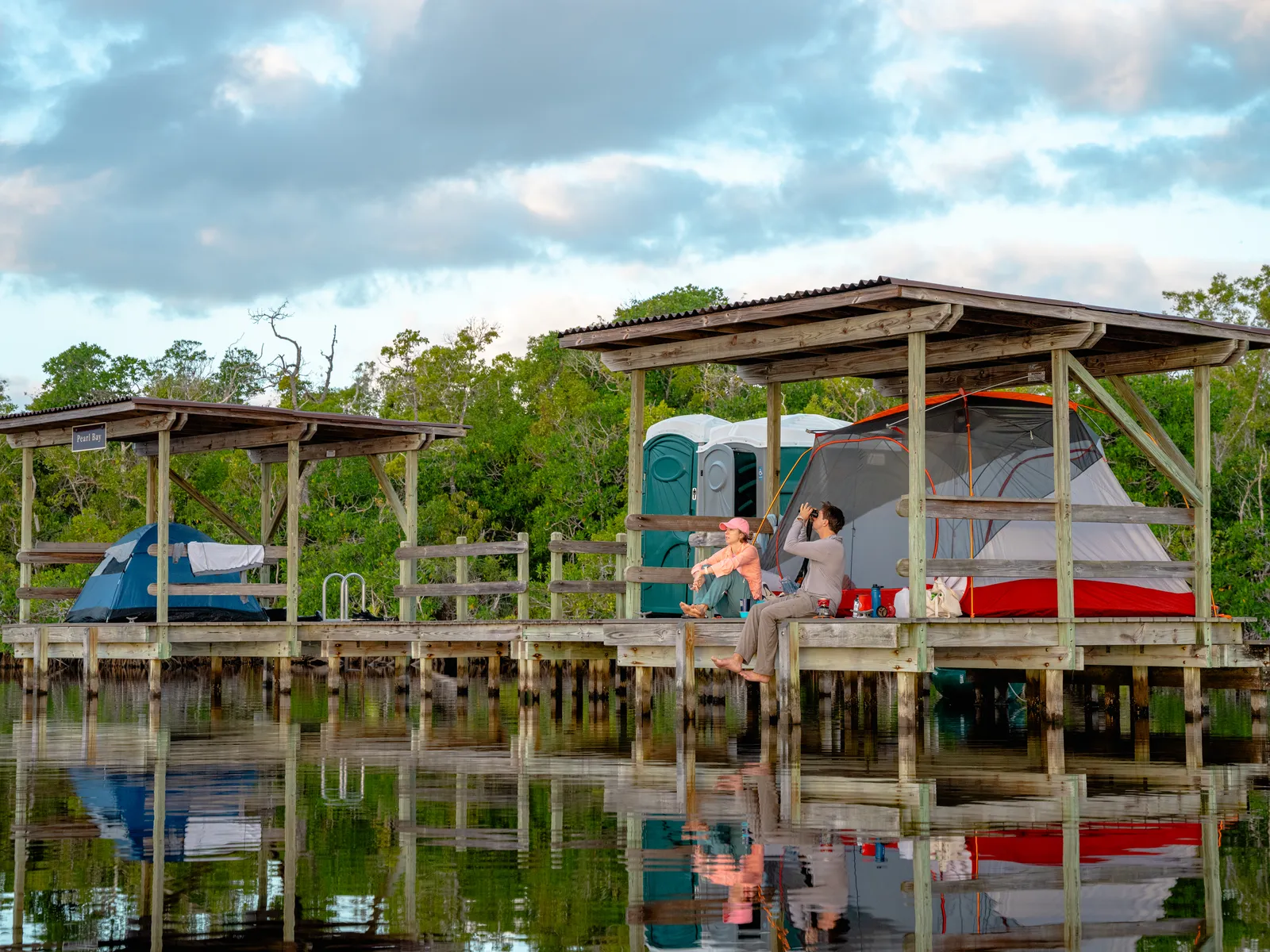 Two campers enjoying a quiet waterside campsite surrounded by Florida wetlands